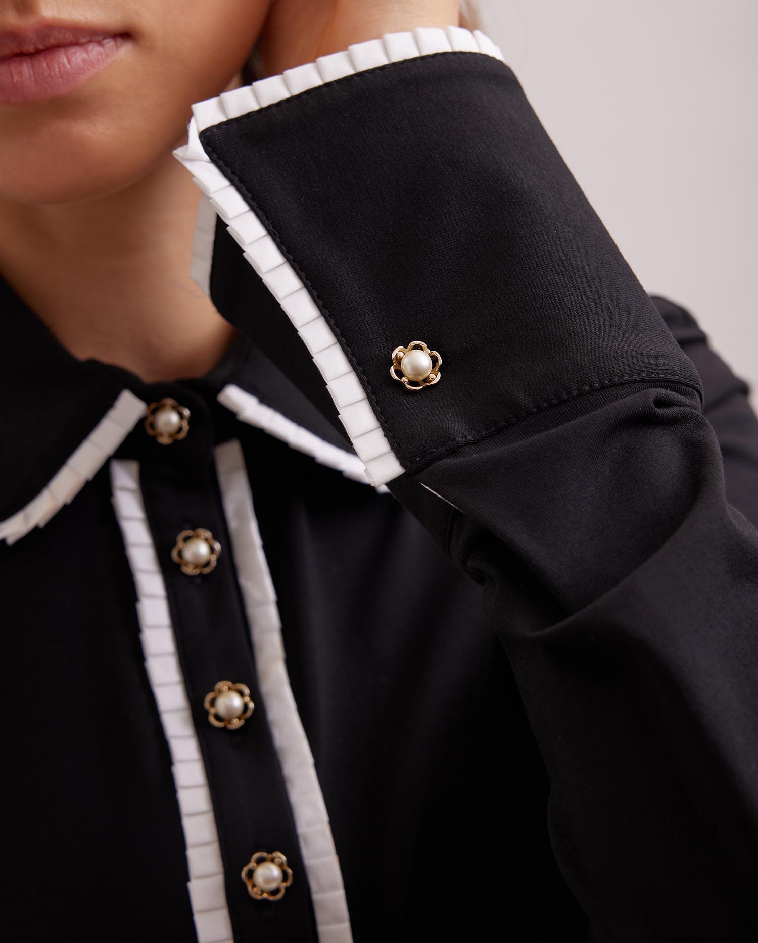 Discover The FAUSTINE black pima knit shirt with white piping and pearl buttons from ANNE FONTAINE.